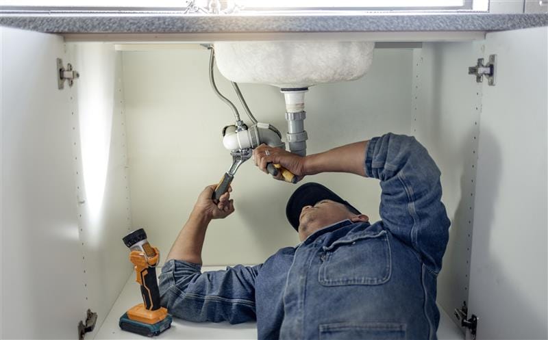 Plumber repairing pipes beneath a bathroom sink in Winter Haven
