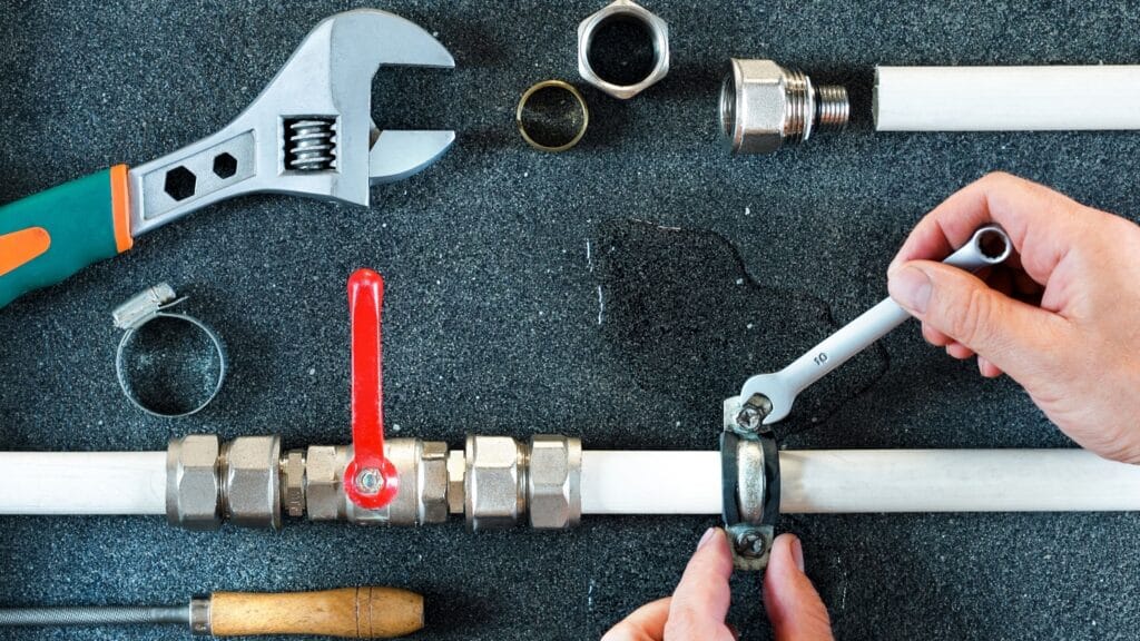 Plumber repairing a pipe valve with an adjustable wrench in Winter Haven