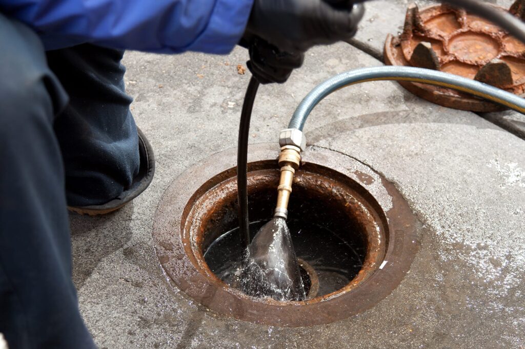 Plumber hydro jetting a sewer line through a manhole in Winter Haven