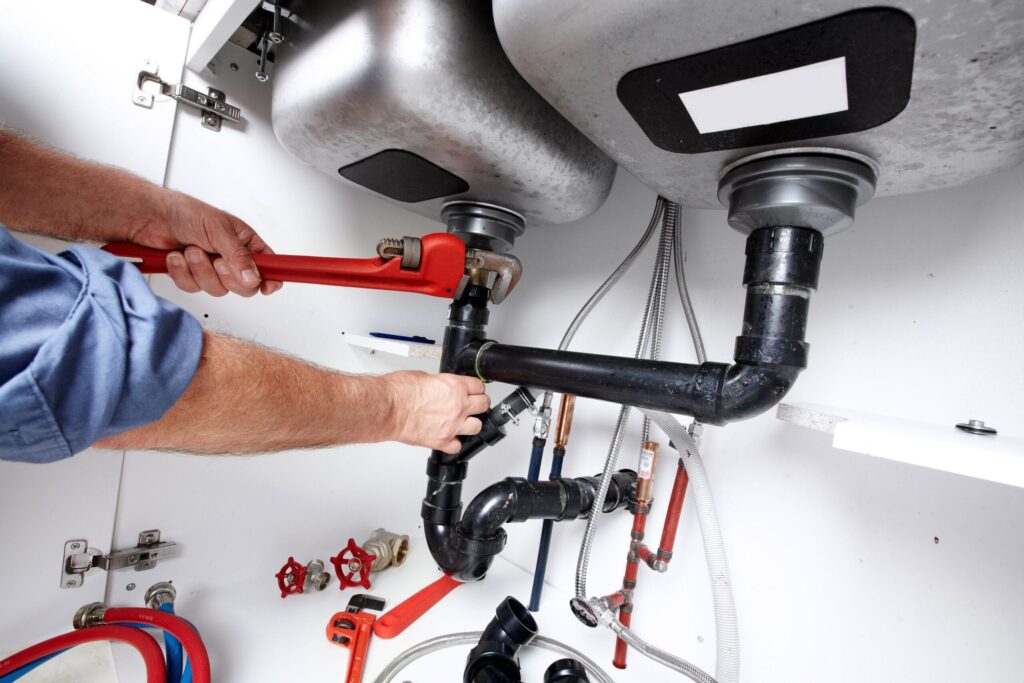 Plumber repairing drain pipes beneath a kitchen sink in Winter Haven