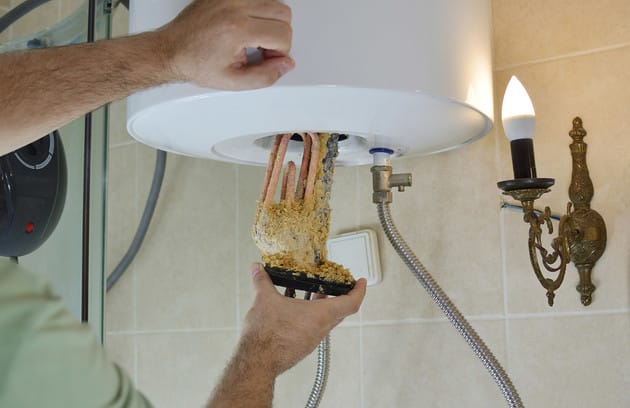 Technician removing mineral buildup from a water heater in Winter Haven